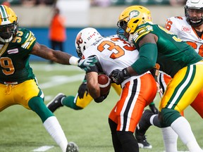 Edmonton's Willie Jefferson (99) and Don Oramasionwu (93) tackle BC's Andrew Harris (33) during the first half of CFL action between the Edmonton Eskimos and the BC Lions at Commonwealth Stadium in Edmonton, Alta.. on Saturday September 26, 2015. Ian Kucerak/Edmonton Sun/Postmedia Network