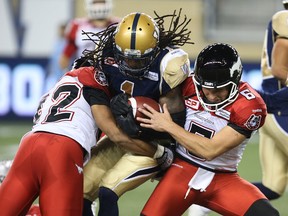 Winnipeg Blue Bombers KR Troy Stoudermire is stopped by Calgary Stampeders LB Deron Mayo (left) and punter Rob Maver during CFL action at Investors Group Field in Winnipeg on Fri., Sept. 25, 2015. Kevin King/Winnipeg Sun/Postmedia Network