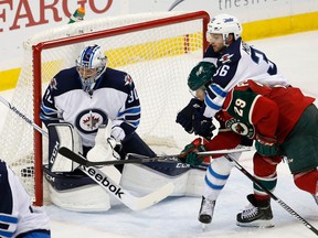 Winnipeg Jets defenseman Joshua Morrissey (36) holds onto Minnesota Wild right wing Jason Pominville (29) as Jets goalie Connor Hellebuyck (30) deflects a shot by Pominville during the third period of an NHL preseason hockey game in St. Paul, Minn., Sunday, Sept. 27, 2015. The Wild won 8-1. (AP Photo/Ann Heisenfelt)