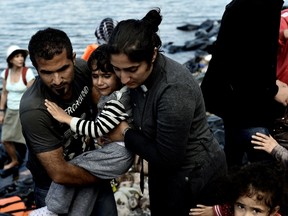 Syrian refugees arrive to the Greek island of Lesbos, after crossing the Aegean Sea from Turkey on September 27, 2015. Some 17 Syrians including five women and five children trying to reach Greece drowned September 27 when their boat sank in Turkish waters, local media reported. AFP PHOTO / ARIS MESSINIS