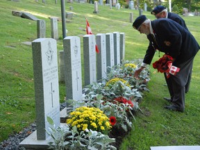Veterans place poppies and small Canadian flags along the six grave markers of the fallen British Commonwealth soldiers who rest at the Glenwood Cemetery during a Veterans' day Ceremony in Picton on Saturday.