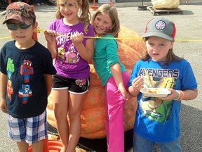 Joey Delima, far left, Kayla Delima, Deliah Parkes and Camry Mahoney post beside a large pumpkin at the Wallaceburg Kinsmen Pumpkinfest held at the Wallaceburg Kinsmen Community Centre on Saturday.