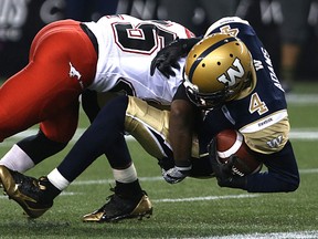 Winnipeg Blue Bombers wide receiver Darvin Adams is hit by Calgary Stampeders defensive back Keon Raymond during CFL action at Investors Group Field in Winnipeg on Sept. 25, 2015. (Kevin King/Winnipeg Sun/Postmedia Network)