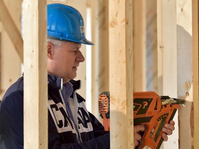 Conservative Leader Stephen Harper uses a nail gun as he makes a campaign stop in Kleinburg, Ont., on Tuesday, September 29, 2015. (THE CANADIAN PRESS/Nathan Denette)