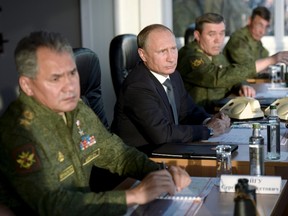 Russian President Vladimir Putin, centre, with Defence Minister Sergei Shoigu, left, and armed forces Chief of Staff Valery Gerasimov observe troops in action during a training exercise at the Donguz testing range in Orenburg region, Russia, on Sept. 19, 2015. (REUTERS/Alexei Nikolsky/RIA Novosti/Pool)