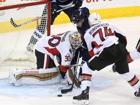 Winnipeg Jets' Nic Petan, centre, drives hard towards Ottawa Senators' goaltender Andrew Hammond, left, before being wrapped up by Mark Borowiecki, who took a game-changing penalty on the play.