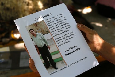 In this Aug. 25, 2015 photo, Yolanda Alvarez Antunez shows a copy of the leaflets she has been posting in the streets seeking information about her missing husband, who was kidnapped two years ago, in Iguala, Mexico. Beto, as he was called, was broad and tall, still strong at the age of 54. Rumored sightings of her husband reach her from time to time.  (AP Photo/Dario Lopez-Mills)