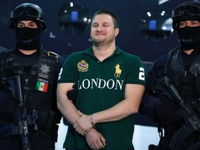 In this Tuesday Aug. 31, 2010, file photo, Federal Police escort Texas-born fugitive Edgar Valdez Villarreal, alias "the Barbie," center, during his presentation to the press in Mexico City. An official said on Wednesday, Sept. 30, 2015, that Mexico is extraditing Valdez Villareal to the United States. (AP Photo/Alexandre Meneghini, File)