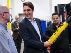 Liberal leader Justin Trudeau lifts an accessory to attach to a forklift during a campaign stop at a forklift dealership in Montreal, on Oct. 1, 2015. (THE CANADIAN PRESS/Paul Chiasson)