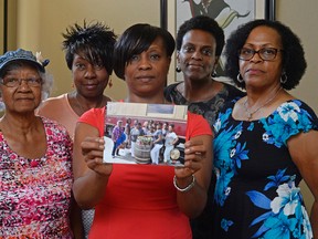 Five members of the Sistahs on the Reading Edge book club, all of Antioch, from left, Katherine Neal, Georgia Lewis, Lisa Renee Johnson, Allisa Carr and Sandra Jamerson stand together at Johnson's home in Antioch, Calif., on Monday, Aug. 24, 2015. The five women were among 11 African-American women who were were booted off the Napa Valley Wine Train on Saturday afternoon. Johnson holds a photograph of the group that was taken before boarding the train. (Jose Carlos Fajardo/Bay Area News Group via AP)