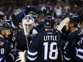 Winnipeg Jets goalie Michael Hutchinson (34) comes to celebrate his teammate's goal after the three on three overtime period against the Calgary Flames at MTS Centre. Winnipeg won 3-1.