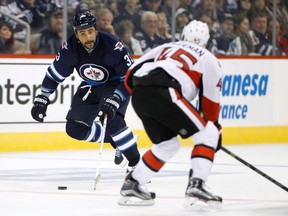 Winnipeg Jets' Dustin Byfuglien, left, tries to carry the puck past Ottawa Senators' Chris Wideman (45) during second period pre-season NHL hockey action in Winnipeg on Tuesday, September 29, 2015.