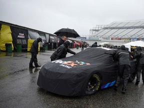 Crew members push Denny Hamlin's car into the garage area Friday, Oct. 2, 2015, at Dover International Speedway in Dover, Del. (AP Photo/Nick Wass)