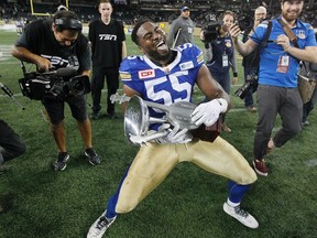 Winnipeg Blue Bombers' Jamaal Westerman (55) strums the Banjo Bowl after defeating the Saskatchewan Roughriders in CFL action in Winnipeg Saturday, September 12, 2015. THE CANADIAN PRESS/John Woods