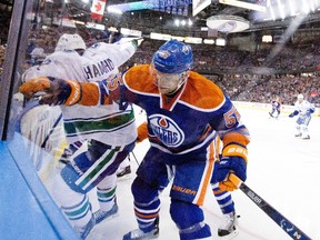 Vancouver Canucks' Dan Hamhuisand Oilers centre Mark Letestu battle in the corner during second-period NHL pre-season action on Thursday at Rexall Place. (The Canadian Press)