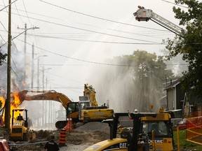 Seen from Elmer Street, firefighters on Yeomans Street direct water onto a burning natural gas line below. The fire destroyed one home but caused no injuries.