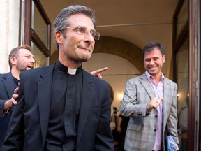 Monsignor Krzysztof Charamsa, center, and his partner Eduard, right,  surname not given, leave a restaurant after a press conference in downtown Rome, Saturday Oct. 3, 2015. Vatican on Saturday fired a monsignor who came out as gay on the eve of a big meeting of the world's bishops to discuss church outreach to gays, divorcees and more traditional Catholic families. (AP Photo/Alessandra Tarantino)
