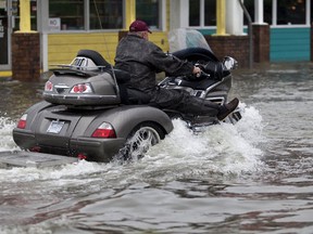 A motorcyclist navigates through flood waters in Garden City Beach, South Carolina, October 2, 2015. Category 4 Hurricane Joaquin is now moving northward and has started bringing swells to parts of the southeastern coast of the United States, the National Hurricane Center said on Friday. (REUTERS/Randall Hill)