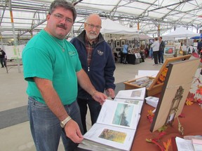 Myles Vanni, left, with the Inn of the Good Shepherd, looks over examples of work by watercolour artist Jack Keefe at Art Under Glass, a fundraiser held at DeGroot's Nursery, on Saturday October 3, 2015 in Sarnia, Ont. (Paul Morden/Sarnia Observer/Postmedia Network)