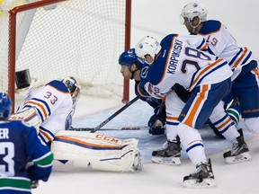Vancouver Canucks' Jannik Hansen, centre,of Denmark, scores against Edmonton Oilers goalie Cam Talbot (33) while being checked by Lauri Korpikoski (28), of Finland, and Justin Schultz (19) during the third period of a pre-season NHL hockey game in Vancouver, B.C., on Saturday October 3, 2015. THE CANADIAN PRESS/Darryl Dyck