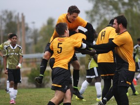 Cambrian Golden Shield men's soccer player Papi gets mobbed by his teammates after scoring the game tying goal in the 82nd minute during OCAA men's soccer action at the Cambrian pitch on Sunday afternoon.