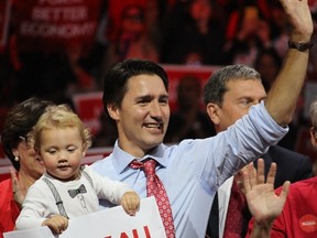 Liberal leader Justin Trudeau waves to the crowd at Brampton's Powerade Centre while his son, Hadrien, holds onto a campaign sign as a rally wraps up. (SHAWN JEFFORDS/Toronto Sun)