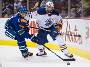 Vancouver's Brandon Sutter and Edmonton's Benoit Pouliot battle for the puck Saturday night (Darryl Dyck, The Canadian Press).