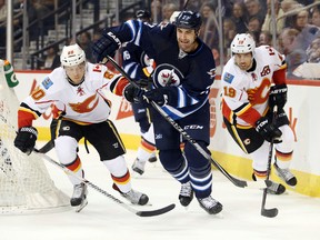 Winnipeg Jets  defenceman  Adam Pardy (2) battles Calgary Flames centre Markus Granlund (60) and Calgary Flames right wing David Jones (19) for the puck during the first period at MTS Centre.