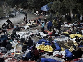 A photo taken on October 5, 2015 shows refugees and migrants a day after they spent a night in a field on the Greek island of Lesbos after crossing the Aegean sea from Turkey on October 5, 2015. Europe is grappling with its biggest migration challenge since World War II, with the main surge coming from civil war-torn Syria. AFP PHOTO / ARIS MESSINIS