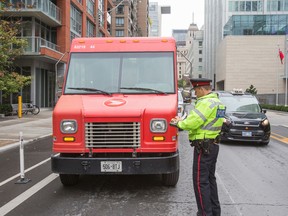 Toronto Police Const. Clint Stibbe writes a ticket for an illegally parked postal truck in the downtown core.