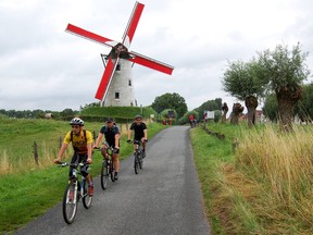 A bike ride along a canal near the Belgian town of Bruges includes a visit to a working windmill with red sails. (photo: Rick Steves)