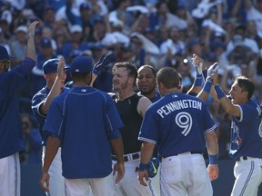 Josh Donaldson #20 of the Toronto Blue Jays is congratulated by teammates at home plate after hitting a game-winning solo home run in the ninth inning during MLB game action against the Tampa Bay Rays on September 27, 2015 at Rogers Centre in Toronto, Ontario, Canada.   Tom Szczerbowski/Getty Images/AFP