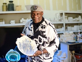 In this Monday, Oct. 5, 2015 photo, former Minnesota Viking football player Carl Eller poses with some of his ceramic artwork, patterned after Minnesota Lakes, that will be part of a display at the new Vikings Stadium.