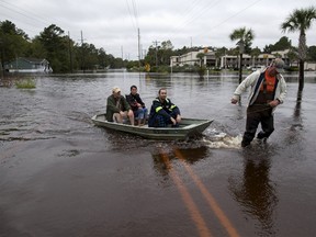 David Carroll (R) of Waccamaw Lake Drive pulls boat carrying neighbors Rick Woodward, Miki Woodward and Matt Desjardins in Conway, South Carolina October 6, 2015. The Woodward family came to the landing from their flooded neighborhood to meet daughter Kelly who had been separated from them for a few days because of the floods. REUTERS/Randall Hill