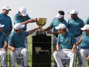 International team players touch the trophy as they attend a photo session for the Presidents Cup golf tournament at Jack Nicklaus Golf Club Korea in Incheon, South Korea, on Tuesday, Oct. 6, 2015. (Ahn Young-joon/AP Photo)