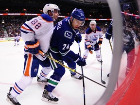 Brandon Davidson battles Canucks' Adam Cracknell in the corner during Saturday's game in Vancouver. (The Canadian Press)