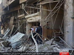 In this Monday, Oct. 5, 2015 photo released by the Rased News Network, a Facebook account affiliated with Islamic State militants, which has been authenticated based on its contents and other AP reporting, people gather at the site of an airstrike in Al-Bab on the outskirts of Aleppo, Syria.   (Rased News Network via AP)