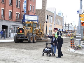 Construction on Elgin Street, between Elm and Ste. Anne Road, resumed on Tuesday October 6, 2015 after being shut down due to a tragic fatality the week before in Sudbury. Paid duty officers will control traffic and pedestrian crossings at the intersections of Elgin and Beech streets and Elgin and Ste. Anne Road during paving operations. Here, Sgt. Marc Brunette helps an elderly pedestrian cross Beech Street in this file photo. Gino Donato/Sudbury Star/Postmedia Network