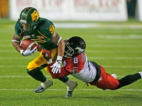 Edmonton Eskimos Kendial Lawrence (32) is brought down by Calgary Stampeders Fred Bennett (8) during their game at Commonwealth Stadium in Edmonton, Alberta on Saturday, September 12, 2015 PERRY NELSON - EDMONTON SUN / QMI AGENCY
