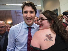 Meghan Gulliver shows off her tattoo to Liberal leader Justin Trudeau during a campaign event at St. Thomas University, in Fredericton on Oct. 7, 2015. The tattoo says "Just Watch Me," in memory of Justin's father Pierre Elliot Trudeau. (THE CANADIAN PRESS/Paul Chiasson)