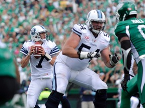 Argos quarterback Trevor Harris (left) won’t have offensive lineman Chris Van Zeyl (centre) to protect him for a while. Van Zeyl is out after injuring his calf against the RedBlacks. (The Canadian Press)