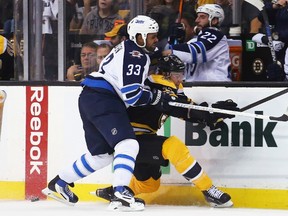 Dustin Byfuglien #33 of the Winnipeg Jets checks Jimmy Hayes #11 of the Boston Bruins into the boards during the Jets 6-2 season-opening win on Thursday night.