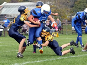 Ingersoll District Collegiate Institute's Dustin Pacheco, centre, is brought down by College Avenue Secondary School's Aaron Yungblut, left, and a teammate in Woodstock, Ont. on Thursday October 8, 2015. CASS won 14-13 in the last minutes of the fourth quarter. (Greg Colgan/Woodstock Sentinel-Review/Postmedia Network)
