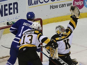 Kingston Frontenacs goalie Lucas Peressini makes a glove save as teammate Konstantin Chernyuk and Mississauga Steelheads Nathan Bastian look on during Ontario Hockey League action at the Rogers K-Rock Centre in Kingston on Friday. Ian MacAlpine/The Kingston Whig-Standard/Postmedia Network
