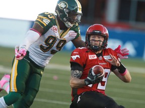 Stamps QB Bo Levi Mitchell is tackled by Eskimos Willie Jefferson during CFL action in Calgary, Alta. between the Edmonton Eskimos and the Calgary Stampeders at McMahon Stadium on Saturday October 10, 2015. Jim Wells/Calgary Sun/Postmedia Network