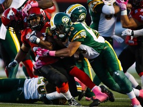 Edmonton’s Aaron Milton, right, brings down Calgary’s Tim Brown at McMahon Stadium in Calgary on Saturday. The Eskimos defeated the Stampeders 15-11 to take over first place. Jeff Mcintosh/THE CANADIAN PRESS
