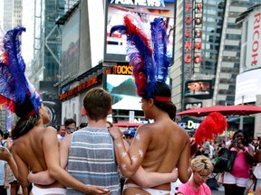 In this July 28, 2015, file photo, a tourist poses for a photo with two women clad in thongs and body paint in New York's Times Square. Topless women posing for photos in Times Square are causing headaches for politicians and law enforcement who wish to regulate their presence but have no clear idea how. (AP Photo/Julie Jacobson, File)
