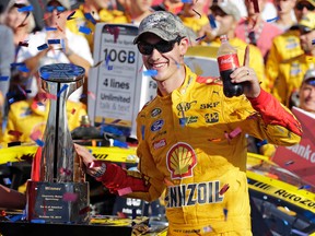 Joey Logano poses with the trophy in Victory Lane after winning the NASCAR Sprint Cup series auto race at Charlotte Motor Speedway in Concord, N.C., Sunday, Oct. 11, 2015. (AP Photo/Terry Renna)