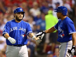 Dioner Navarro #30 of the Toronto Blue Jays celebrates with Ben Revere #7 after scoring a run off Ryan Goins #17 against Martin Perez #33 of the Texas Rangers during game three of the American League Division Series on October 11, 2015 in Arlington, Texas.   Ronald Martinez/Getty Images/AFP