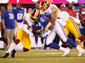 Washington Redskins strong safety Trenton Robinson and Keenan Robinson tackle New York Giants' Daniel Fells during the first half of an NFL football game Thursday, Sept. 24, 2015, in East Rutherford, N.J. (AP/Kathy Willens)